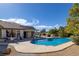 Backyard with a sparkling blue swimming pool, patio furniture, lush landscaping and clear blue sky at 5858 Majestic Tide Ave, Las Vegas, NV 89131