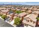 An aerial view shows a neighborhood with terracotta-roofed houses, green trees, and desert scenery at 6046 Bassio Ave, Las Vegas, NV 89141