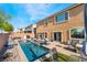 A private pool is surrounded by patio seating and a tan two-story home with an arched window at 6047 Ancient Peaks Ave, Las Vegas, NV 89141