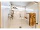 Luxurious marble-look shower with glass door, bench, handheld sprayer, and gold towels at 6047 Ancient Peaks Ave, Las Vegas, NV 89141