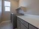 Well-lit laundry room with gray washer and dryer, white countertop, and a window at 6433 Farness St, Las Vegas, NV 89135