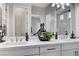 Well-lit bathroom with a double vanity, decorative mirrors, and a glass-enclosed shower at 689 Moonstone Beach Pl, Henderson, NV 89011