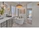 Modern bathroom featuring a soaking tub, dual sinks, marble counters, and natural light at 8848 Rainbow Ridge Dr, Las Vegas, NV 89117