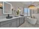 Modern bathroom featuring a soaking tub, dual sinks, marble counters, and natural light at 8848 Rainbow Ridge Dr, Las Vegas, NV 89117