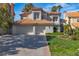 Stunning two-story home featuring a tile roof, three-car garage, and lush landscaping under a clear blue sky at 8848 Rainbow Ridge Dr, Las Vegas, NV 89117