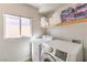 Bright laundry room featuring a modern washer and dryer set, with a window providing natural light at 9124 Sapphire Ridge Ave, Las Vegas, NV 89129