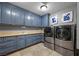 Spacious laundry room with ample blue cabinets and modern stainless steel washer and dryer at 9301 Verlaine Ct, Las Vegas, NV 89145
