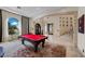 Well-lit living room with pool table, arched window, and elegant staircase in the background at 9301 Verlaine Ct, Las Vegas, NV 89145