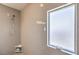 Contemporary shower with neutral tile, adjustable shower head, and frosted window for privacy at 9326 Noble Sage Ave, Las Vegas, NV 89148