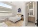 Bright bedroom featuring a bed, modern furniture, and a connecting bathroom with chevron patterned walls at 10752 Patina Hills Ct, Las Vegas, NV 89135