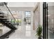 Bright, open foyer with soaring ceilings, statement staircase, and eye-catching chandelier and modern tile flooring at 10752 Patina Hills Ct, Las Vegas, NV 89135