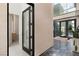 Modern foyer with black framed glass doors, neutral walls and a glimpse of a bathroom with textured walls at 10752 Patina Hills Ct, Las Vegas, NV 89135
