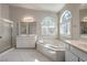 Luxurious primary bathroom with a soaking tub, glass-enclosed shower, double sinks, and ample natural light at 1563 Cattle Ranch Pl, Henderson, NV 89002
