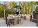 Entertain in the outdoor kitchen with a built-in grill, bar seating, and a lush tropical backdrop at 2240 Boutique Ave, Henderson, NV 89044