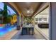 Covered patio with a dining table, seating area, and a view of the sparkling pool and the open-concept living/kitchen area at 2240 Boutique Ave, Henderson, NV 89044