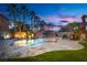 Backyard oasis featuring a gorgeous pool with a waterfall and palm trees set against a stunning twilight sky at 3924 Diamond Ridge St, Las Vegas, NV 89129