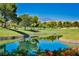 Scenic golf course view with a tranquil pond, vibrant flowers, and rolling green hills, framed by mature trees at 42 Gulf Stream Ct, Las Vegas, NV 89113