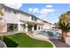 Home's backyard features a pool, jacuzzi, artificial turf, and mature palm trees, perfect for outdoor enjoyment at 5225 Villa Dante Ave, Las Vegas, NV 89141