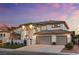 Stunning two-story house featuring lush greenery, an arched entryway, and a three car garage at 5225 Villa Dante Ave, Las Vegas, NV 89141