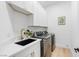 Well-lit laundry room features a large utility sink, modern washer/dryer, and bright white cabinets at 5225 Villa Dante Ave, Las Vegas, NV 89141