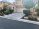 Street view of a beige two-story home with a two-car garage and landscaped front yard at 5653 Nobleton Ct, North Las Vegas, NV 89081