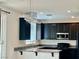 Modern kitchen featuring dark cabinetry, granite countertops, stainless steel appliances, and a decorative chandelier at 5653 Nobleton Ct, North Las Vegas, NV 89081