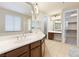 Bright bathroom featuring double sinks, a vanity, and a view into the walk-in closet at 623 Blue Snow River Ct, Henderson, NV 89002