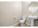 Neat half bath featuring a pedestal sink, round mirror, and toilet in a neutral-toned, well-lit space at 6743 Windingwood St, Las Vegas, NV 89148