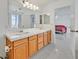 Bright bathroom featuring dual sinks, wood cabinets, large mirror and an adjacent bedroom at 7925 Placid St, Las Vegas, NV 89123