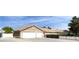 A tan single-story house featuring a three-car garage, desert landscaping, and a secure gated front yard at 7925 Placid St, Las Vegas, NV 89123