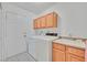 Well-lit laundry room with washer, dryer, utility sink, cabinets, and exterior door at 7925 Placid St, Las Vegas, NV 89123