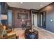 Living room with a brick accent wall, display cabinets, comfortable chairs, and interesting decor at 7938 Jessamy St, North Las Vegas, NV 89084