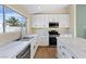 White kitchen featuring marble countertops, stainless appliances, and a window with a palm tree view at 7957 Lovely Pine Pl, Las Vegas, NV 89143