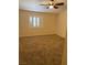 Neutral carpeted bedroom featuring a ceiling fan and bright natural light from the window at 807 Airy Hill St, Henderson, NV 89015