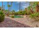 Tropical backyard pool featuring lush greenery, rock features, and brick pavers at 8199 Pinnacle Peak Ave, Las Vegas, NV 89113