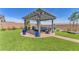 A beautiful backyard boasts a covered patio area with comfortable seating, landscaping, and low-maintenance artificial turf at 10266 Sweet Holly Pl, Las Vegas, NV 89149