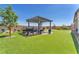 Backyard boasts an expansive artificial lawn and covered patio area with outdoor seating, and tasteful landscaping at 10266 Sweet Holly Pl, Las Vegas, NV 89149