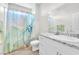 Bright bathroom features a granite countertop, white cabinets, and shower with colorful curtain at 10266 Sweet Holly Pl, Las Vegas, NV 89149