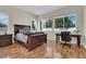 Comfortable bedroom featuring wood floors, a dark wood bed frame, and bright windows with a view at 1116 Piazza Telle, Henderson, NV 89052