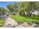 Landscaped backyard featuring lush green grass, manicured shrubbery, tall mature trees, and stone walkway at 1925 Grey Eagle St, Henderson, NV 89074