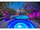 Backyard pool and spa illuminated with blue lights surrounded by trees, and comfortable outdoor seating at 1925 Grey Eagle St, Henderson, NV 89074
