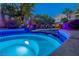 Backyard pool and hot tub illuminated with blue lights and lush landscaping at 1925 Grey Eagle St, Henderson, NV 89074