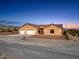 A charming tan single-story home with a three-car garage and desert landscape at 2051 Saginaw Ave, Pahrump, NV 89048