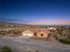 Wide angle twilight picture of a one story tan home with a three car garage and desert landscaping at 2051 Saginaw Ave, Pahrump, NV 89048