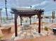 Outdoor pergola with picnic table, desert landscaping, and a community pool in the background at 2064 Mesquite Ln # 304, Laughlin, NV 89029
