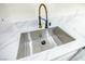 Up-close of a stainless steel sink featuring a black and gold faucet and white marble countertops at 208 N Bruce St # A, Las Vegas, NV 89101