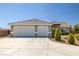 Exterior of a home with a spacious driveway leading to an attached two-car garage with white doors at 230 S Weeping Willow Ct, Pahrump, NV 89048
