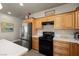 Kitchen featuring wood cabinets, stainless steel refrigerator, and black appliances at 230 S Weeping Willow Ct, Pahrump, NV 89048