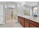 Modern bathroom featuring double sinks, a walk-in shower with a glass door, and neutral tile flooring at 2383 Elmont Ave, North Las Vegas, NV 89086
