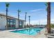 Modern pool with ample seating and palm trees adjacent to community building, under a clear blue sky at 2383 Elmont Ave, North Las Vegas, NV 89086